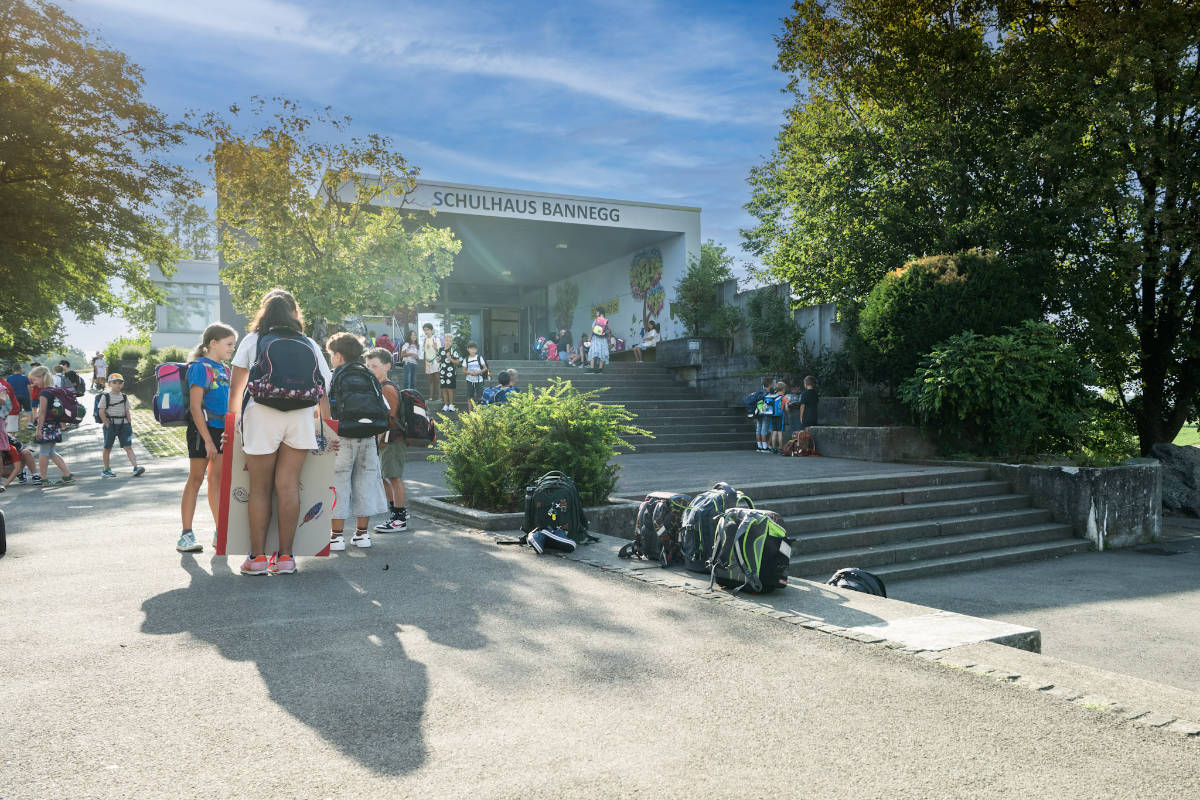 Kinder mit ihren Schulsachen vor dem Schulhaus Bannegg