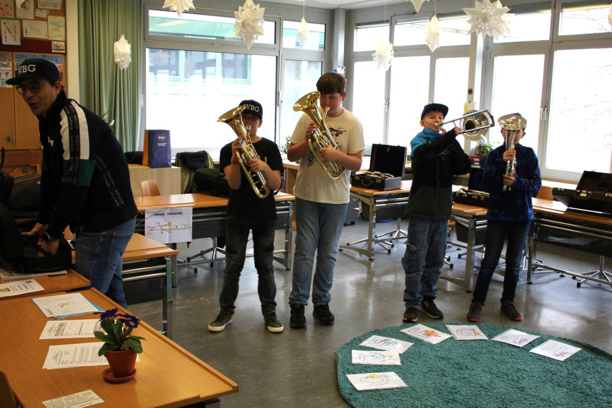 Vier Kinder spielen Blechblasinstrumente im Musikzimmer