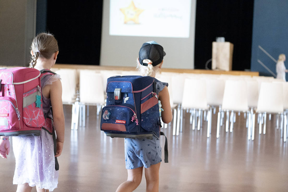 Zwei Kinder mit Schulranzen gehen durch die Bannegghalle zur Feier